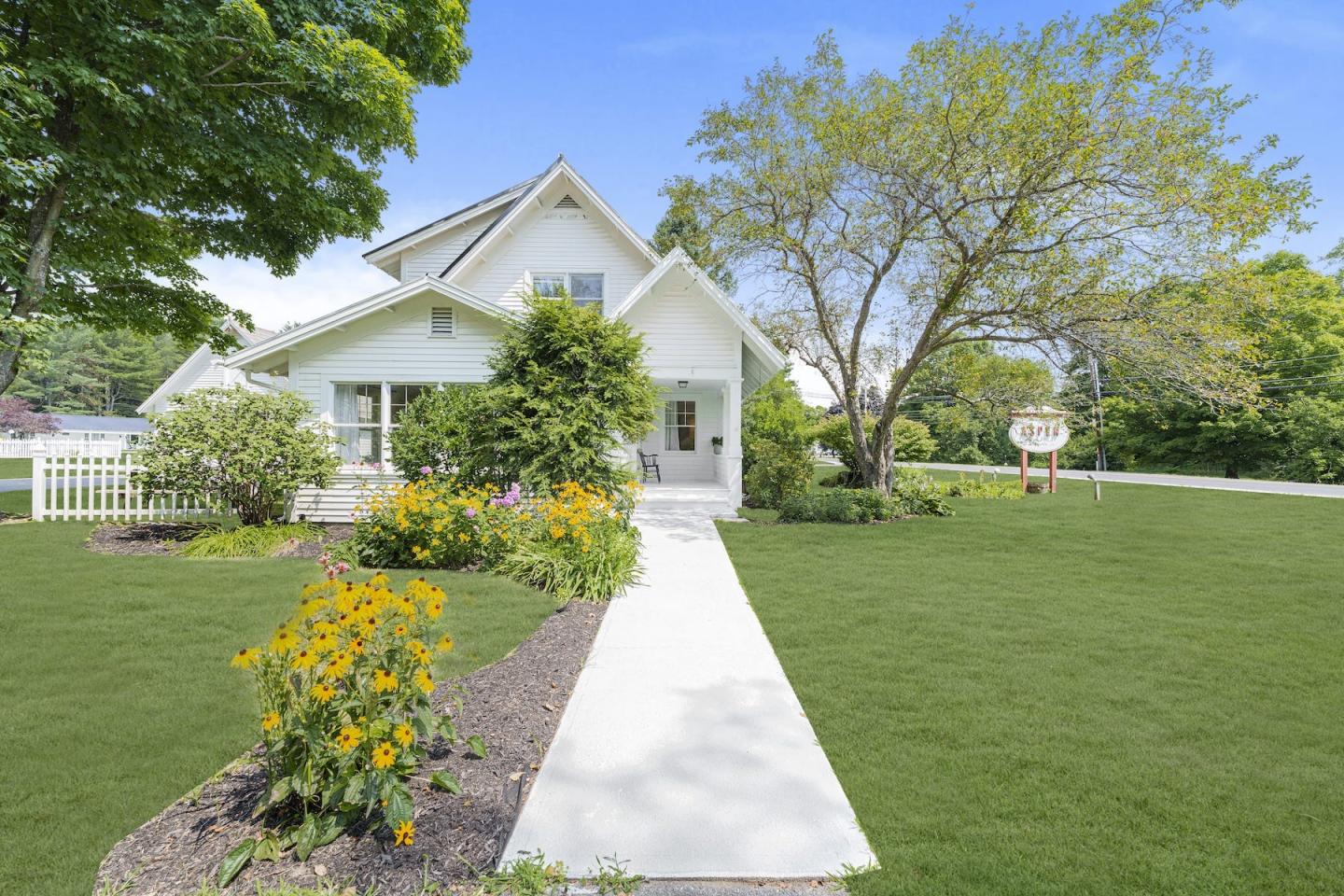 White house with a flower-lined walkway and neatly mowed lawn.