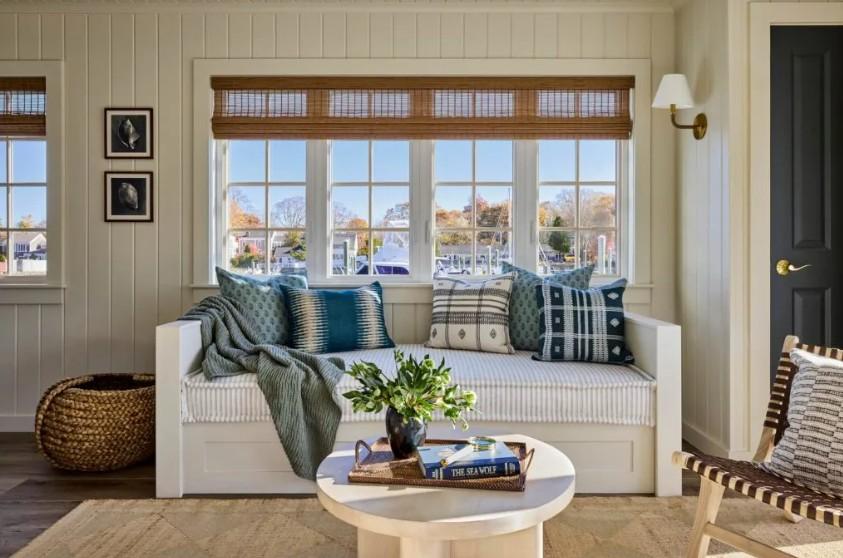 Cozy living room with blue patterned cushions, round coffee table, and large windows.