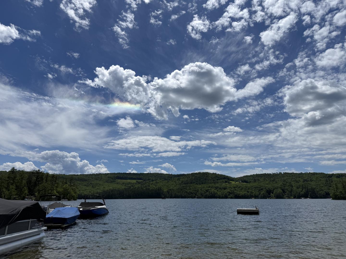 Boats on a lake beneath a dramatic, cloud-filled blue sky.