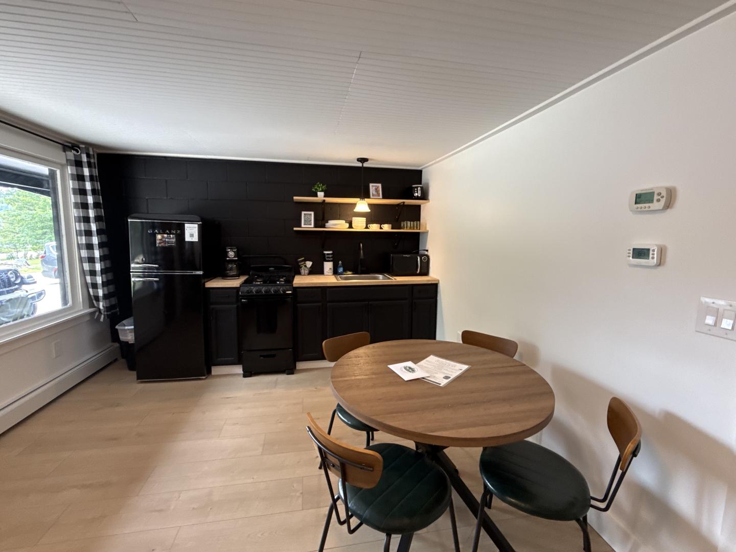 Modern kitchen with black cabinets, round wooden dining table, and white walls.