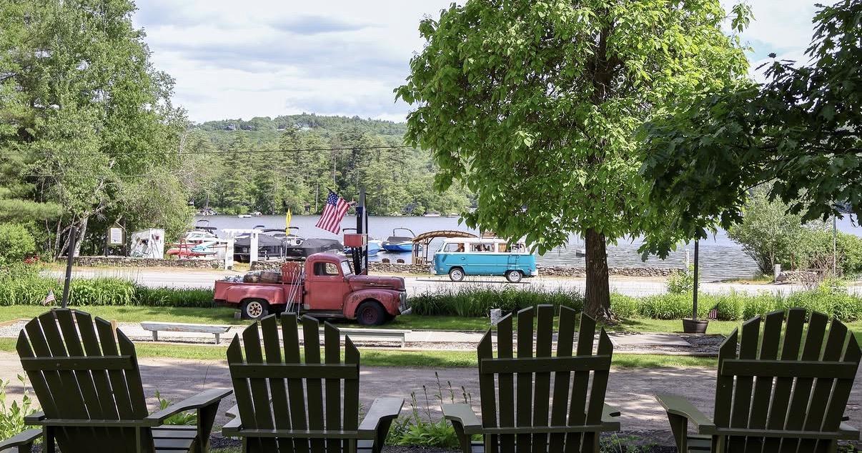 Fire trucks parked across a street, viewed from a shaded porch with Adirondack chairs.