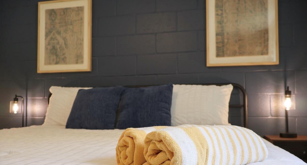 Cozy bedroom with navy pillows, framed art, and a striped blanket on the bed.
