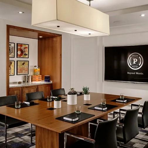 Modern conference room with wooden table, black chairs, and wall-mounted logo screen