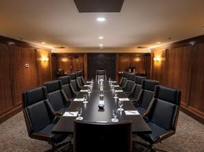 Elegant wood-paneled conference room with a long table and black chairs.
