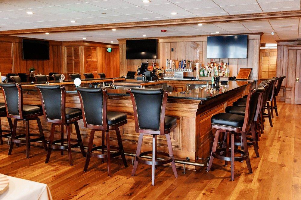 Warm wood-paneled bar with high stools and polished hardwood floors.