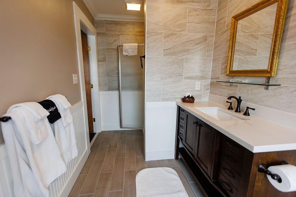 Modern bathroom with double vanity, bathtub, glass shower, and beige tile.
