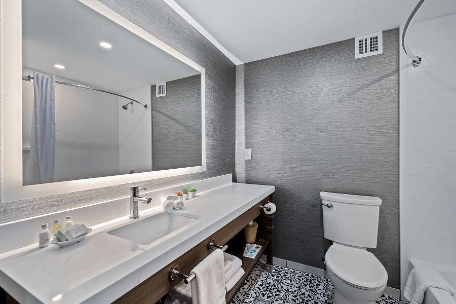 Modern gray bathroom with double vanity, large mirror, toilet, and patterned tile floor.