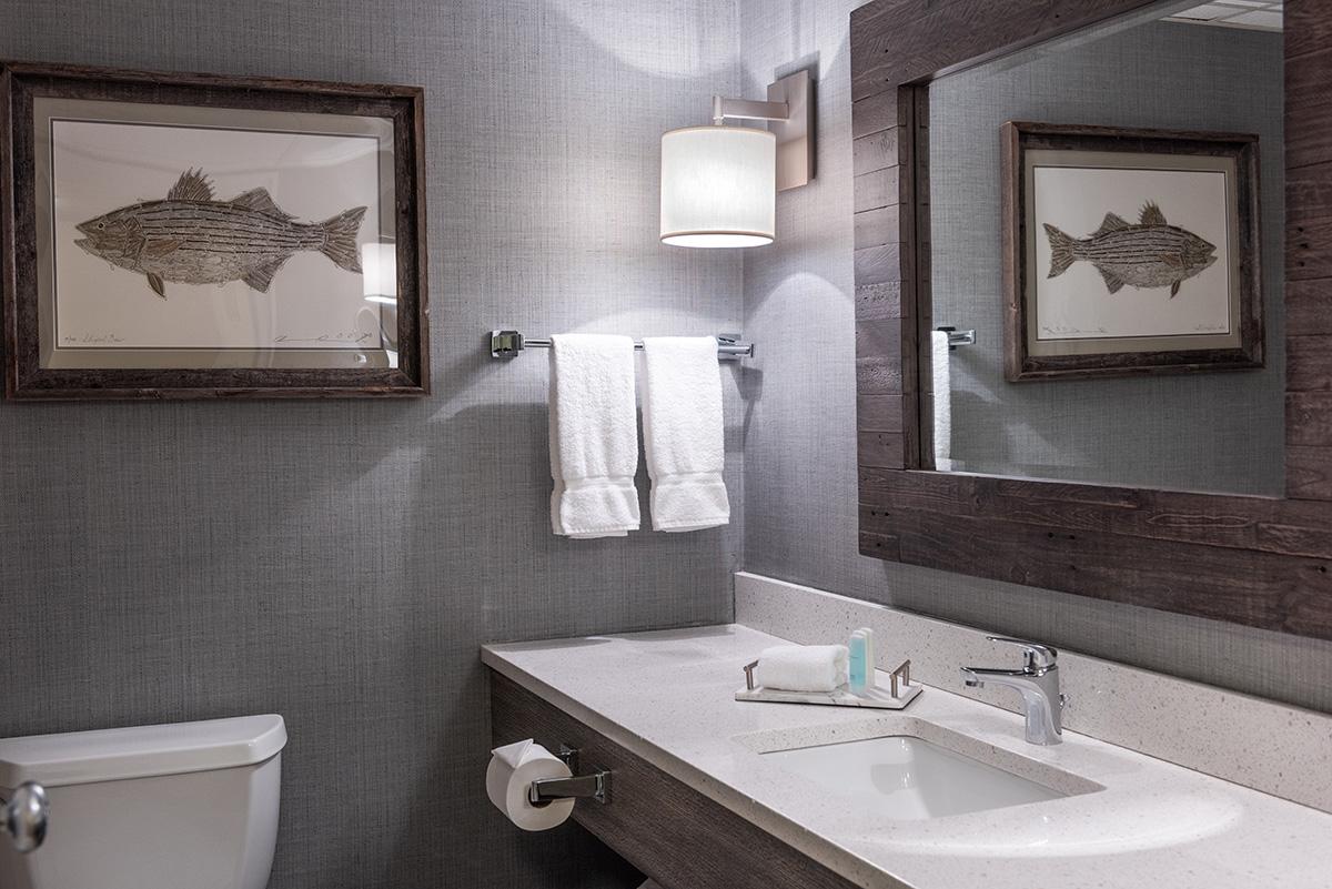Modern gray bathroom with white sink, towel rack, and framed fish artwork