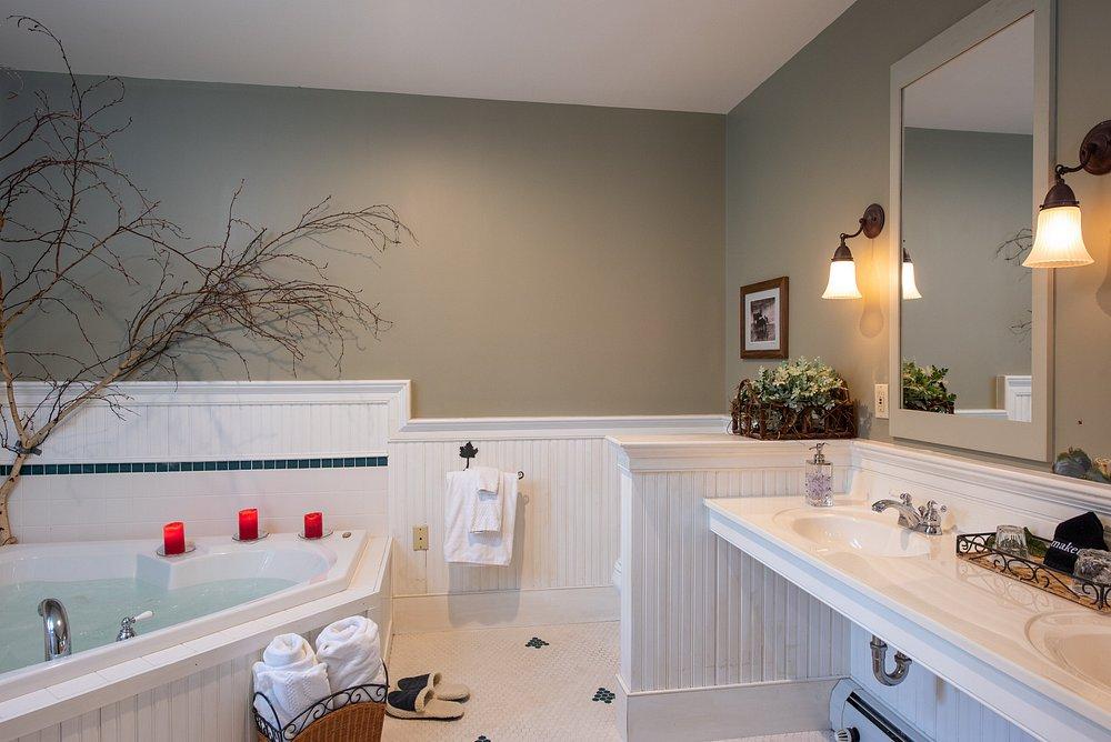 Bright bathroom with white vanity, freestanding tub, and lit mirrors.