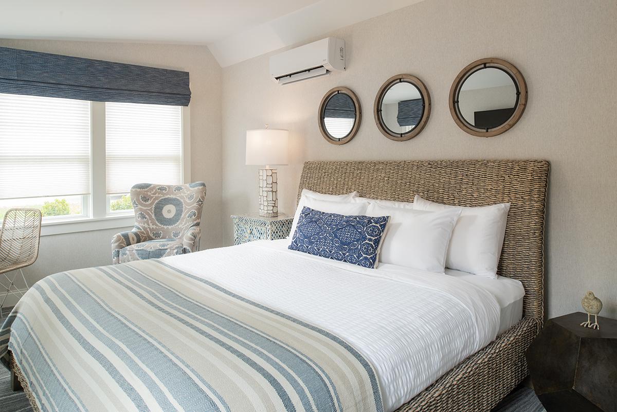 Bright bedroom with a patterned bedspread, upholstered bed, and three round mirrors.