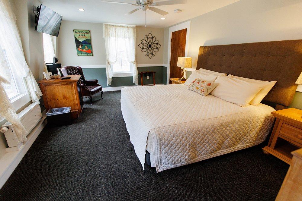 Bright hotel bedroom with a large bed, desk, armchair, and garden view.