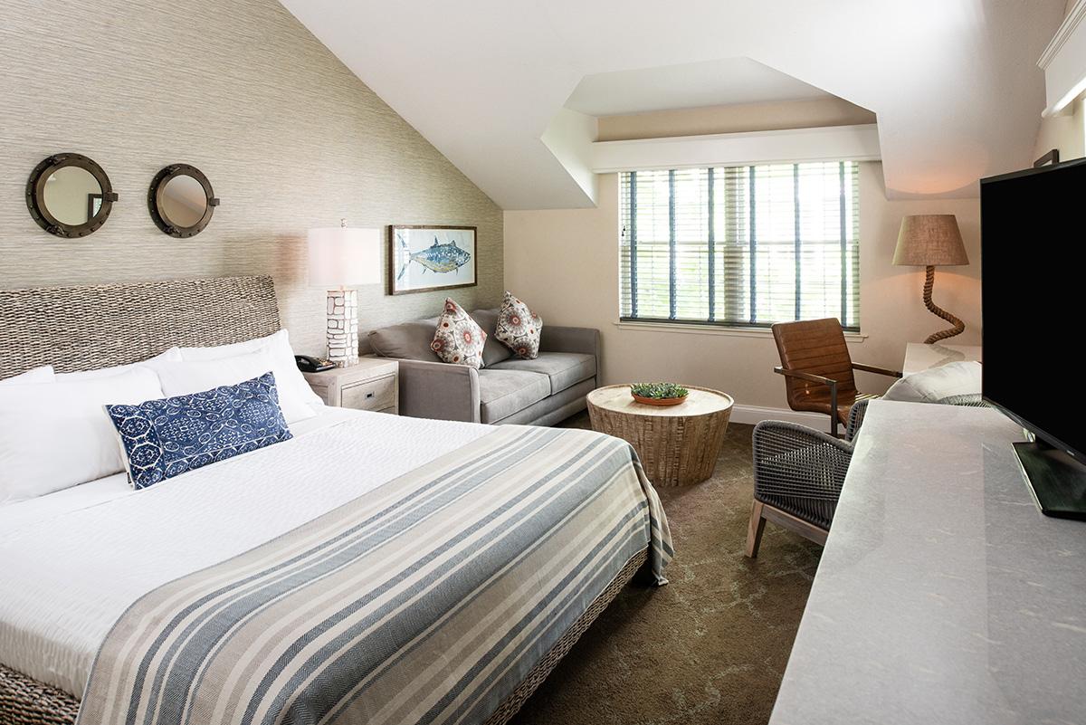 Cozy bedroom with striped bed, seating area, and large window.