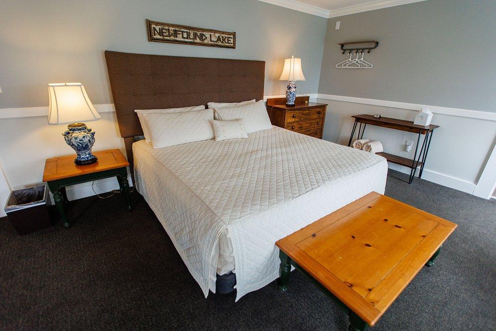 Cozy bedroom with a large white bed, bedside lamps, desk, and wooden bench.