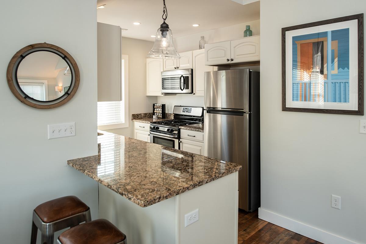 Modern kitchen with granite island, stainless appliances, and framed artwork.