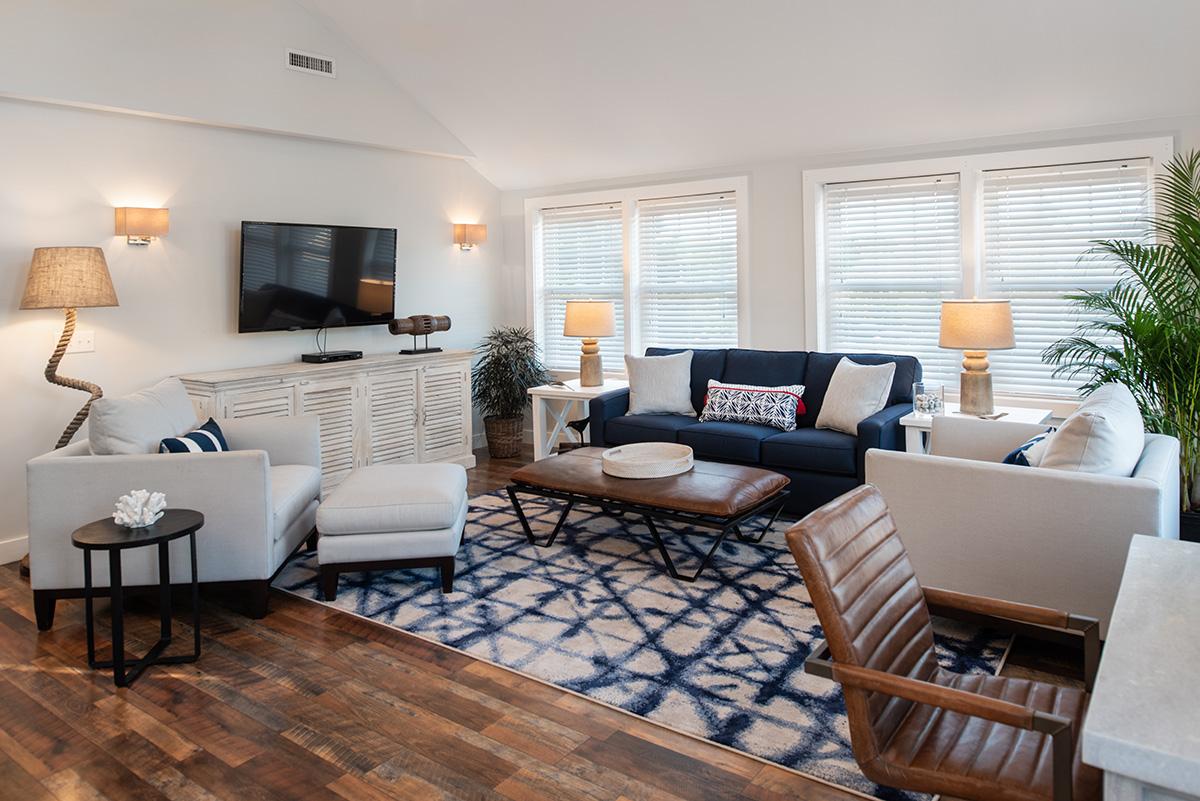 Bright, modern living room with navy accents, patterned rug, and wood furniture.