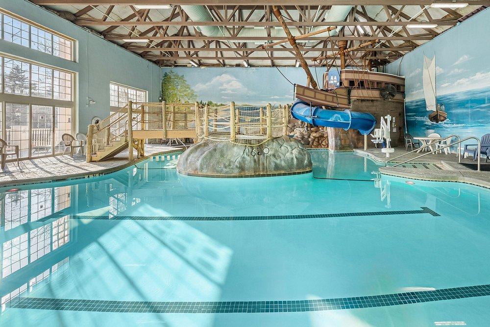 Indoor water park pool with a blue waterslide and tropical mural.