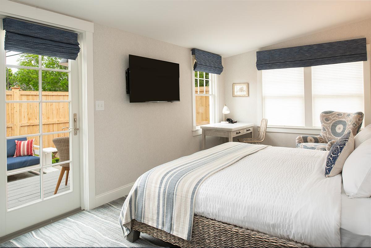 Bright bedroom with striped bedding, gray blinds, and a wall-mounted TV
