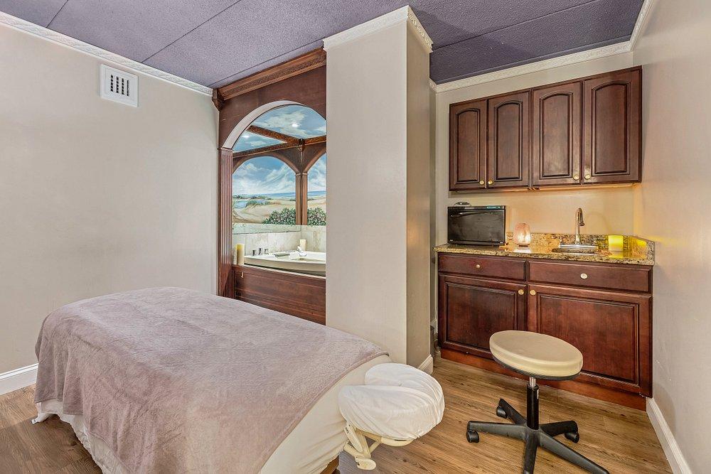 Bedroom with a bed, window seat, and wooden desk with swivel chair