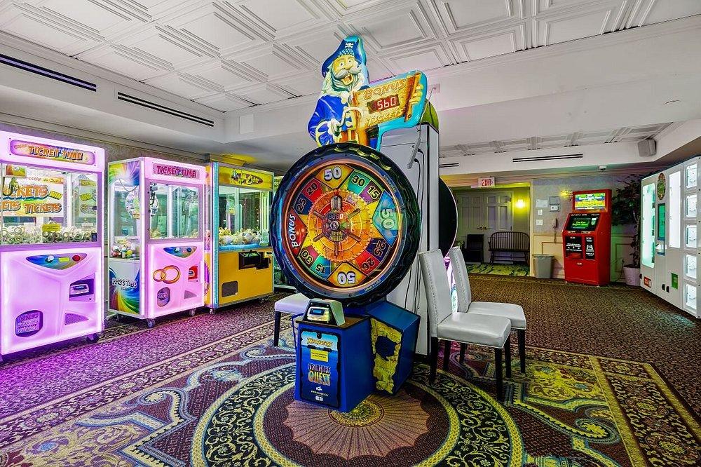 Colorful arcade with a large wheel game, claw machines, and patterned carpet.