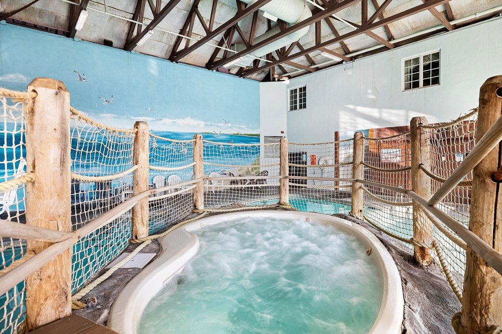 Indoor hot tub with bubbling water, surrounded by wooden railings and blue walls.