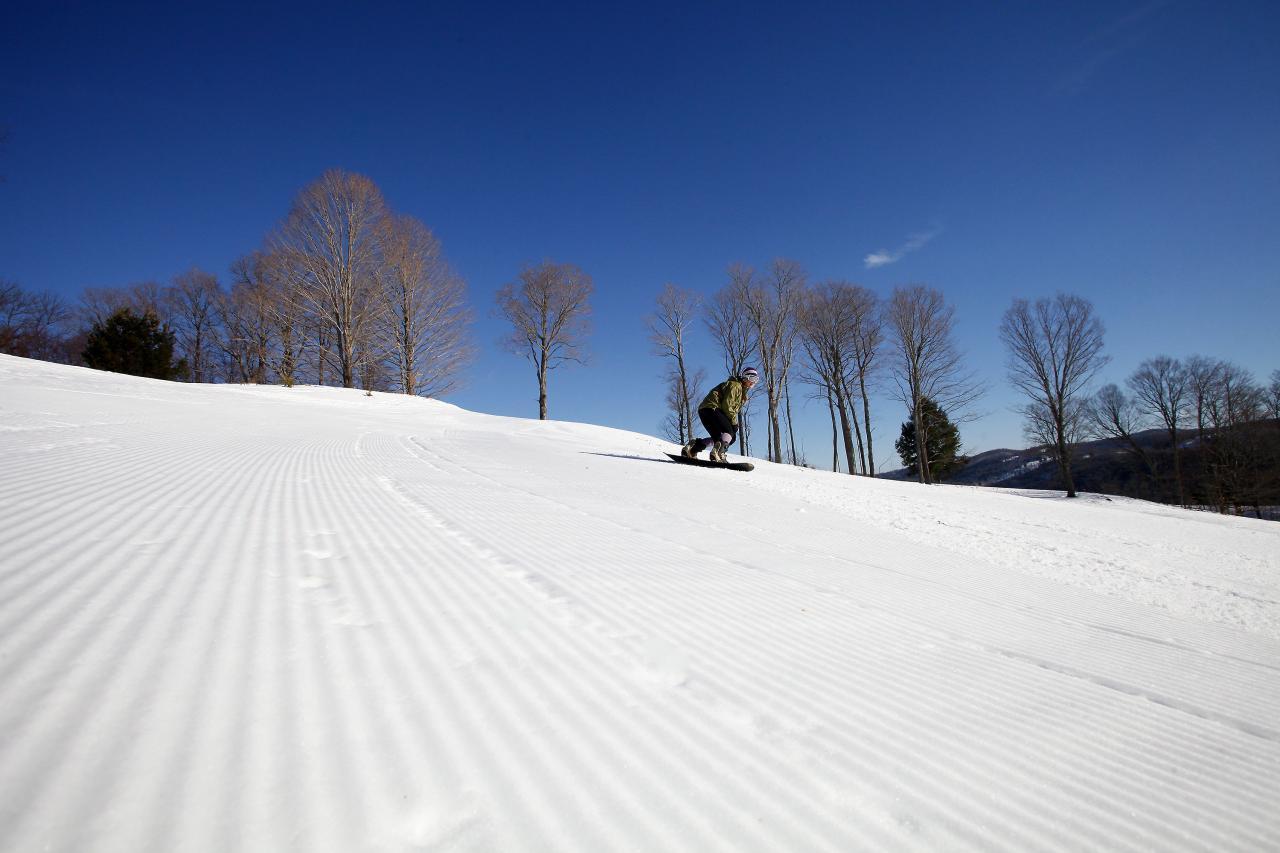 Closeup of groomed ski trail and skier in the background