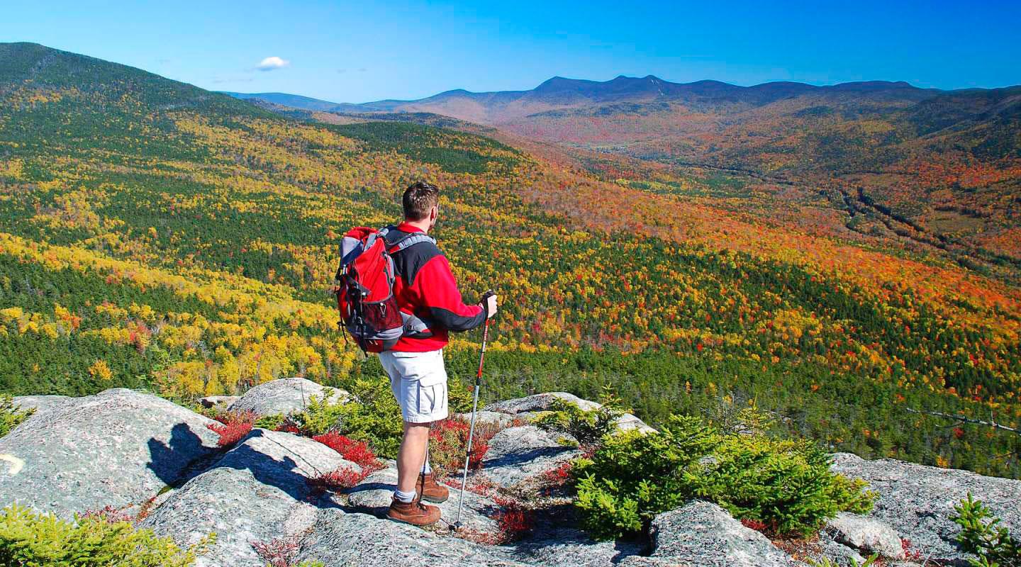 Hiker looking over a scenic hillside of fall foliage