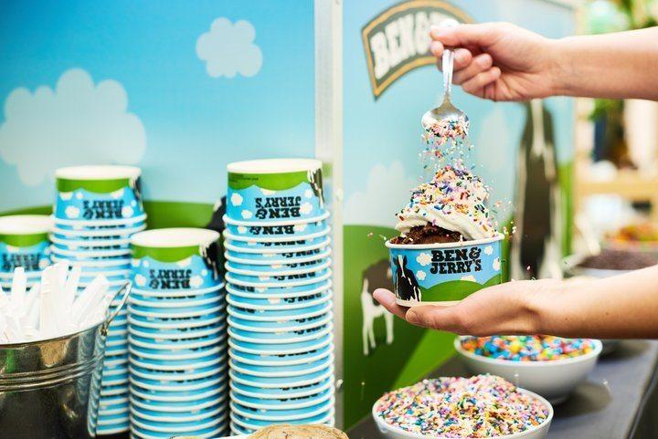 Person's hands springling sprinkles onto ice cream in a cup