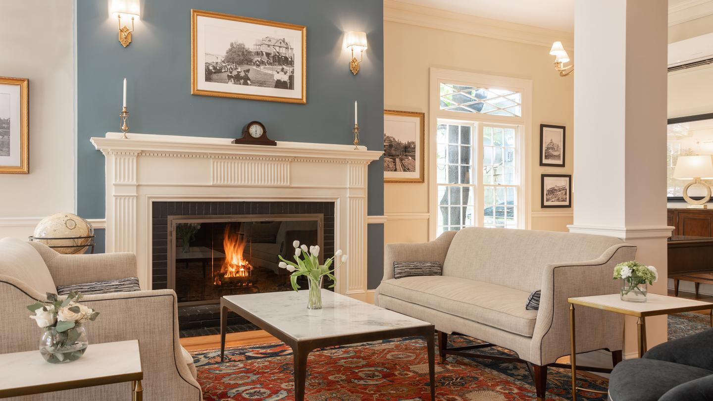 Sitting area in the lobby of the Bar Harbor Inn with couches set by a fireplace.