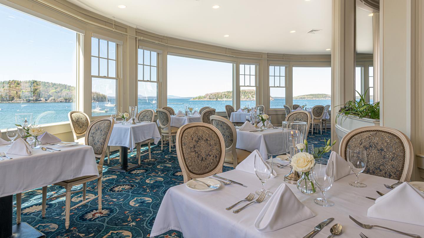 Dining tables set for dinner in the Reading Room restaurant overlooking the water.