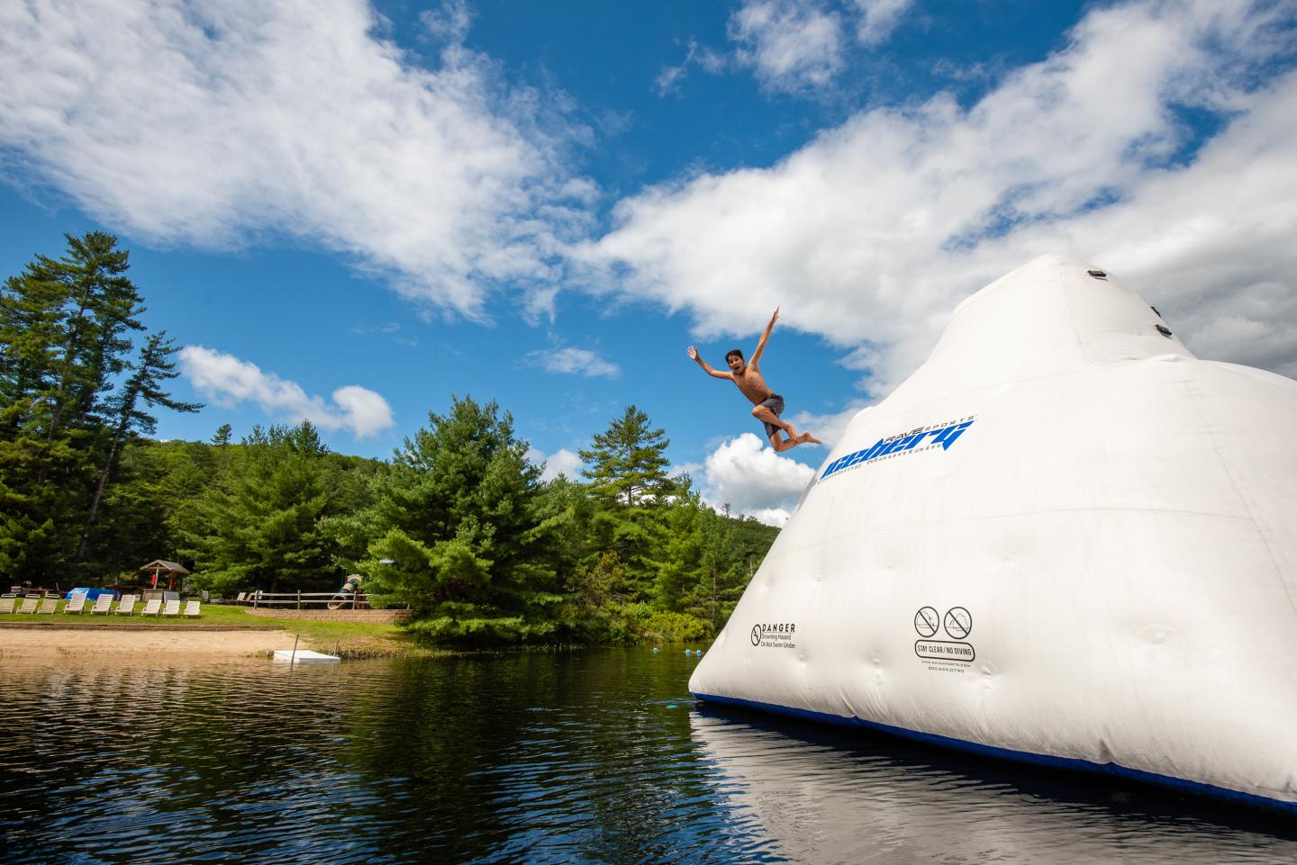 Boy jumping off inflatable iceberg at Purity Spring Resort