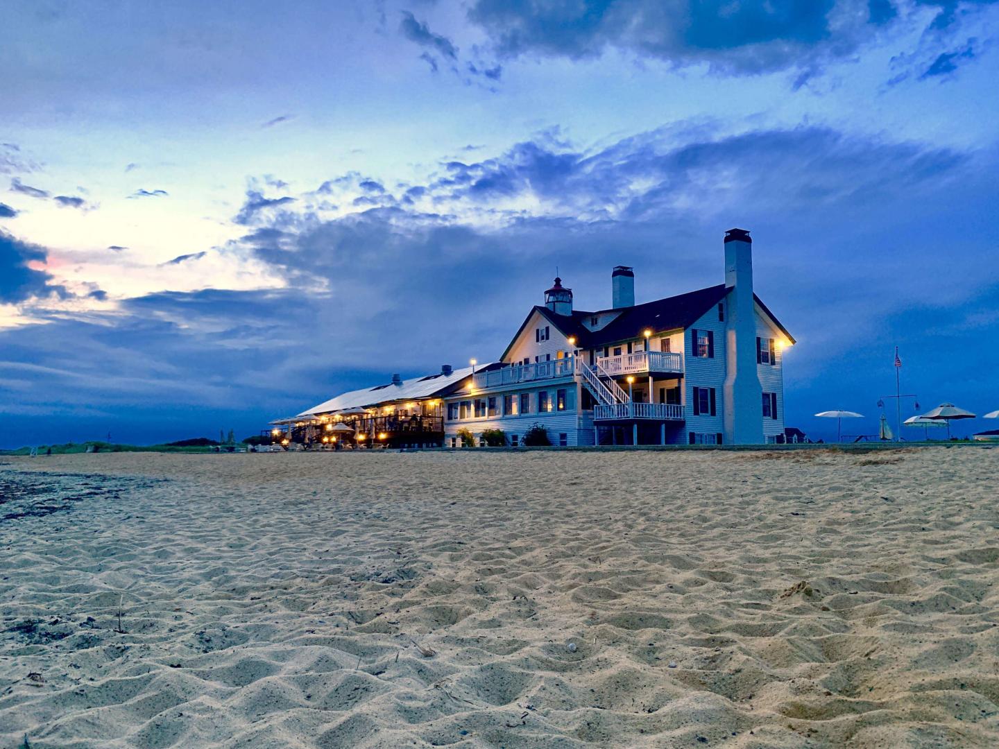 A Lighthouse sits atop keeper's quarters shot from the beach in early light.