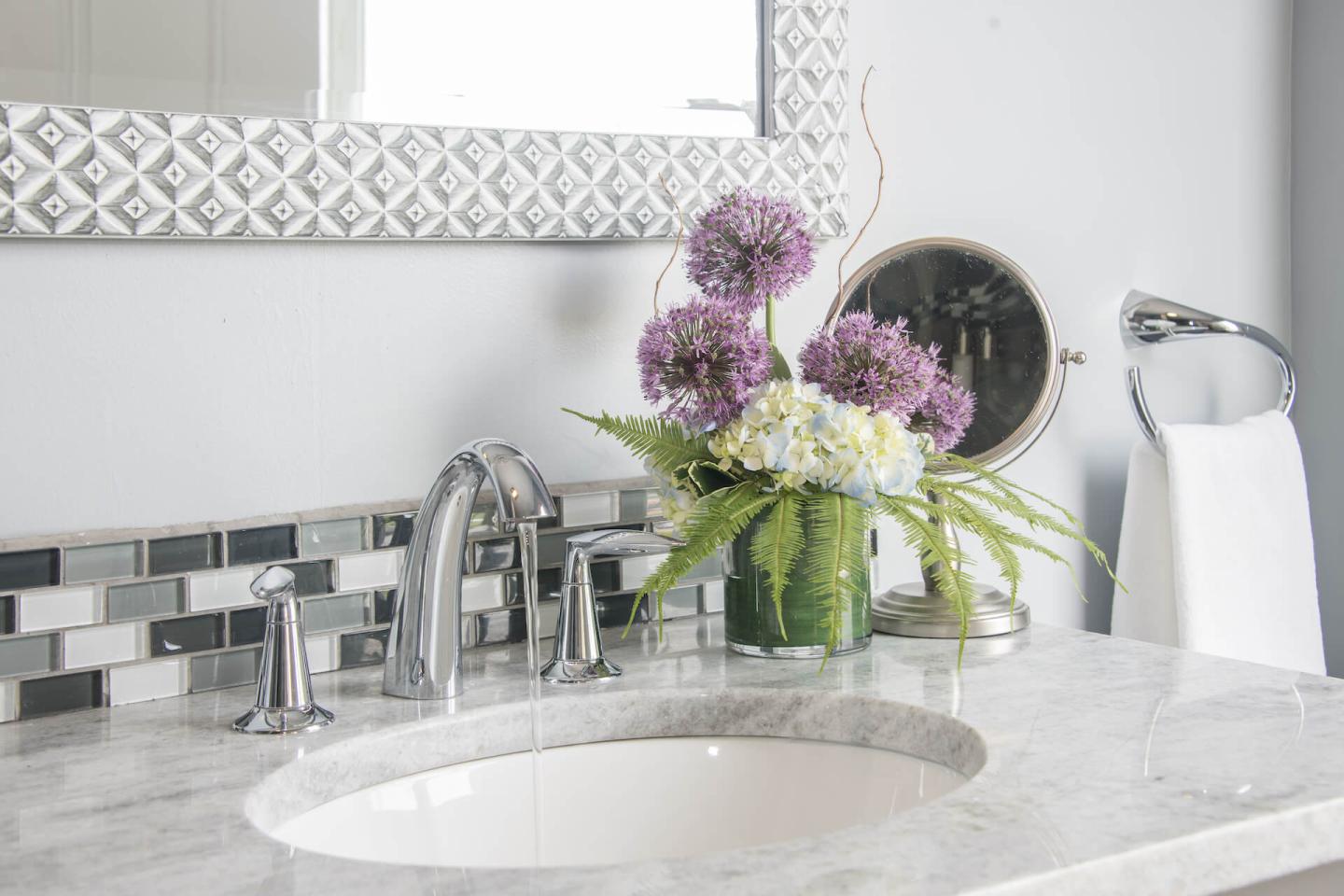 Guest room bathroom with grey tile, a walk-in glass shower, and vanity