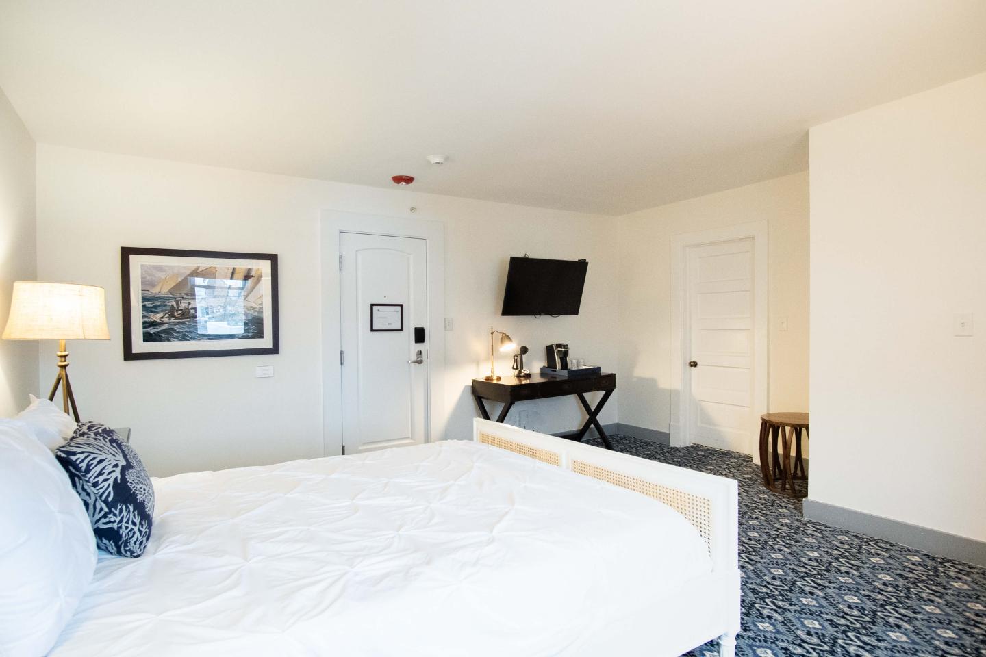 queen bed and a desk. A TV is hanging on the wall above the desk.