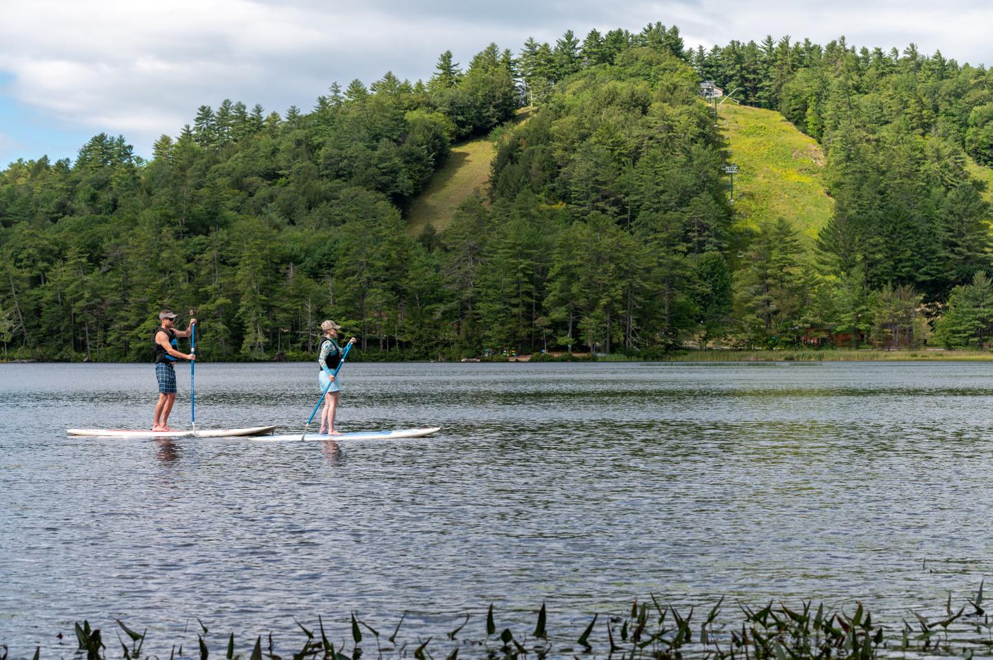 Two people standup paddle boarding on Purity Lake at Purity Spring Resort