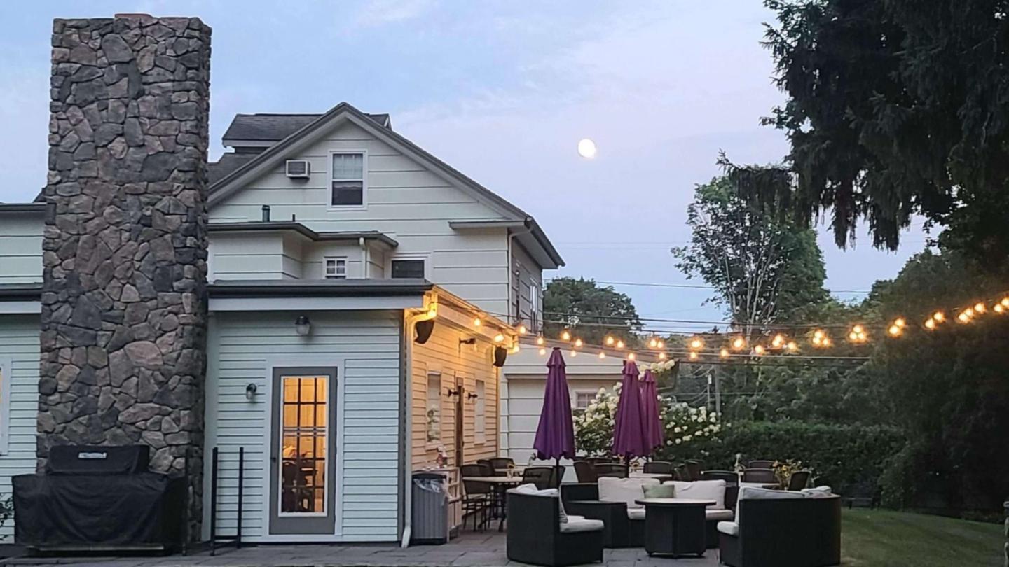 Patio with comfortable sofas lounging at sunset with decorative string lights.