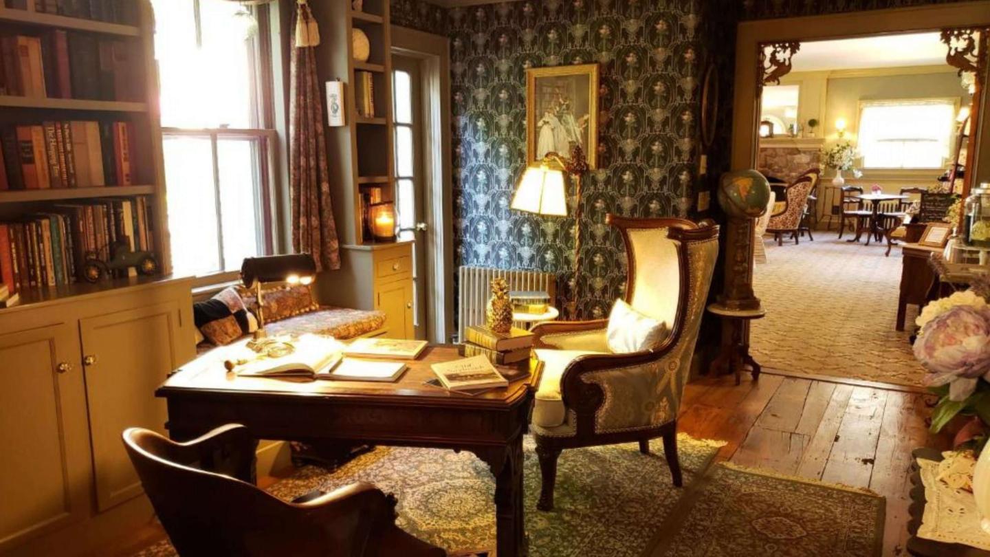 A common area is decorated with antique victorian style furniture and a wooden desk.