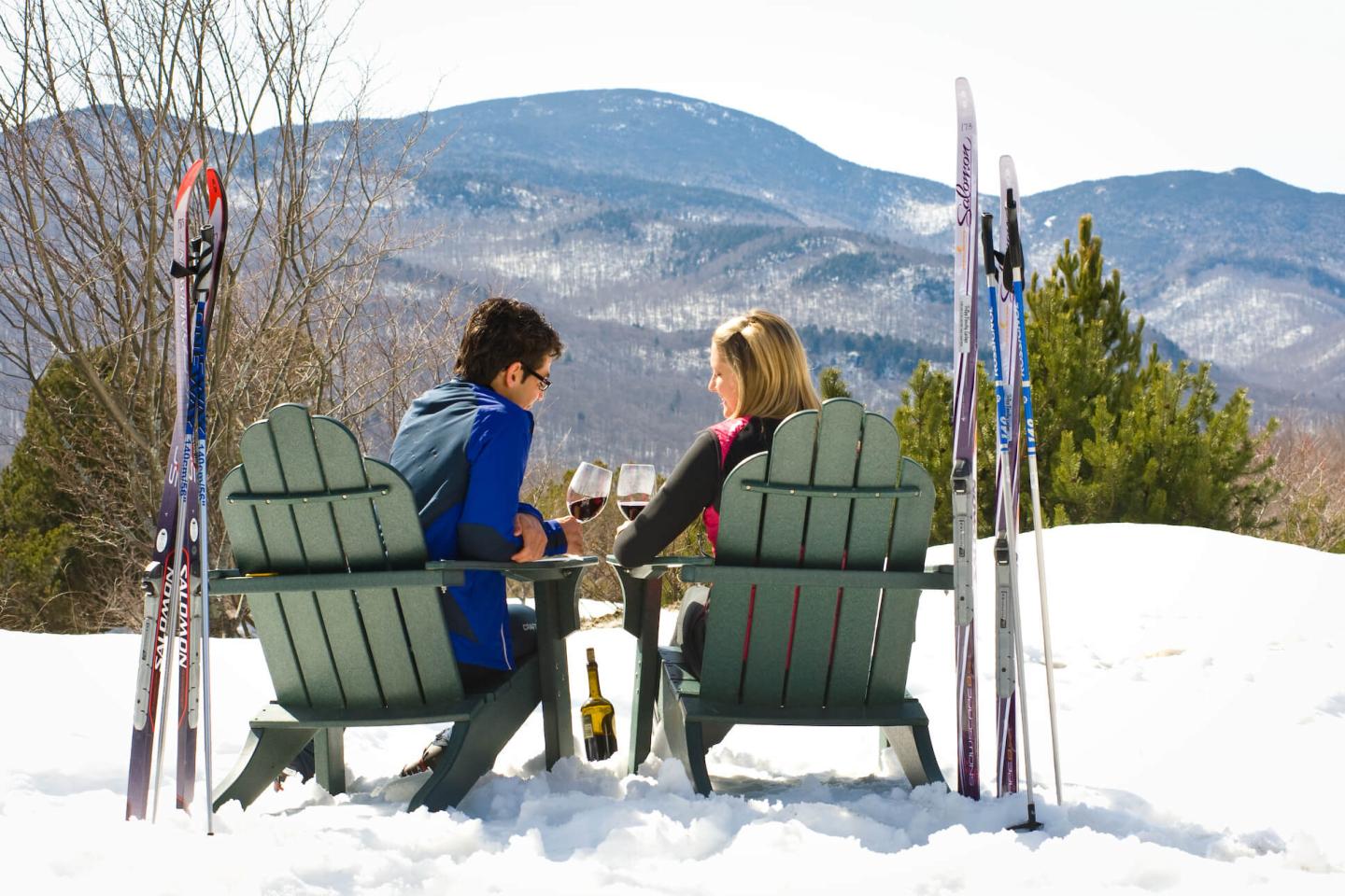 Couple overlooking mountains with skis and wine