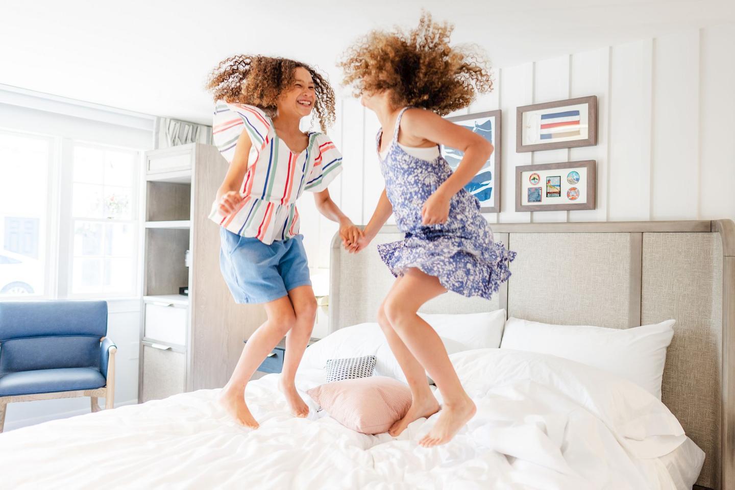Two young girls jumping on the bed