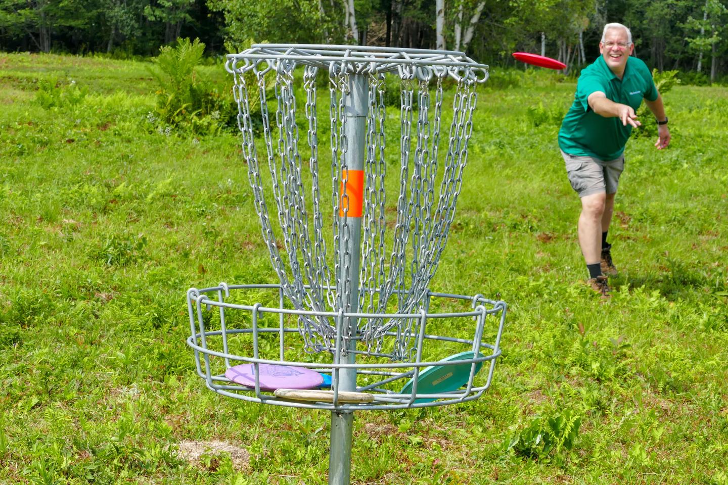 Man playing disc golf with metal net hole