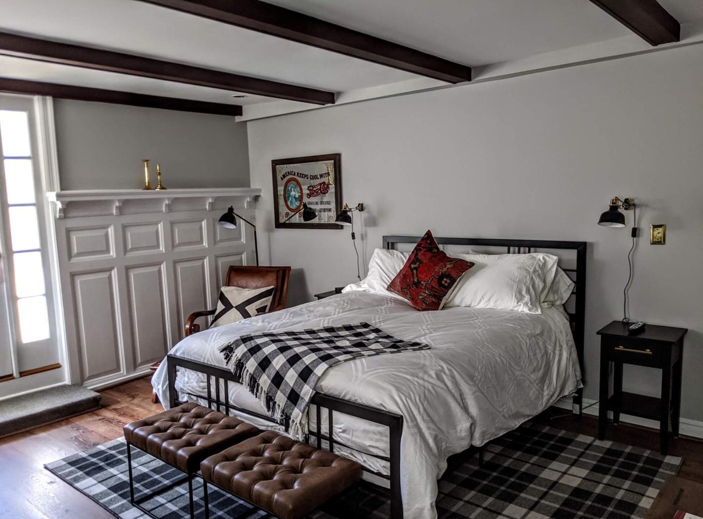 Guest bedroom at Stanton House Inn with a metal bedframe and dark ceiling rafters in the former billiards room