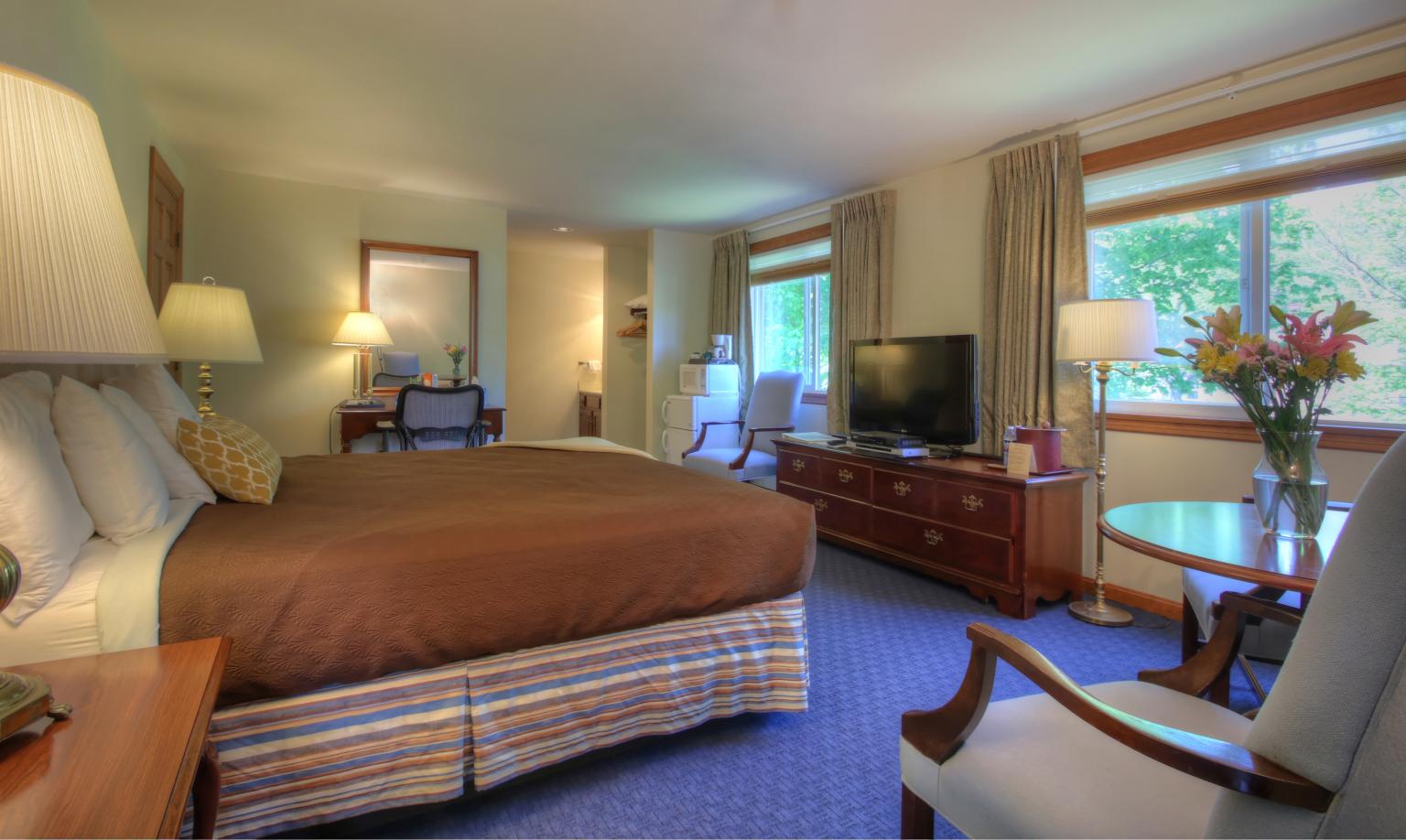 king bed, desk, chair in room with windows overlooking the river