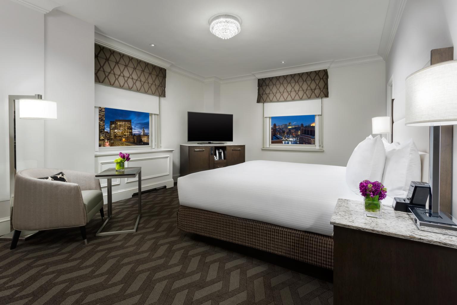A king deluxe room with a bed, tv, chair and floorlamp