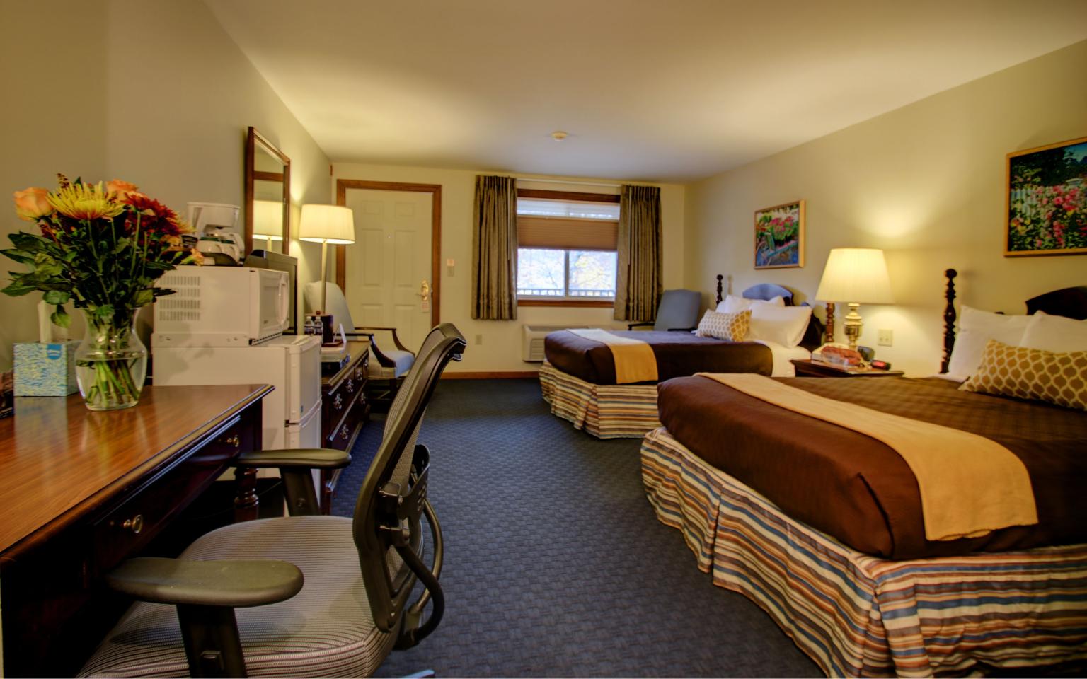 two double beds, desk and tv in hotel room