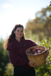 Woman in Fleece holding basket of hand-picked apples